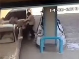 Man is sandwiched between two cars at a gas station.