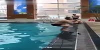 Man does a back onto the ground at the pool