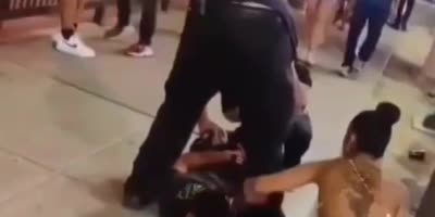 Brazen couple try to steal gold chain off man's neck while he is lying handcuffed on the ground by security in Las Vegas.(R)