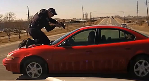 Officer with gun steps on car hood to stop fleeing man