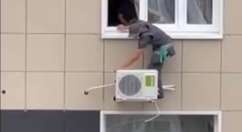A fearless master who installs an air conditioner while standing on a bracket.