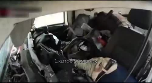 The corpse of a Ukrainian with his legs torn off is pulled out of a car that was hit by a Russian mine