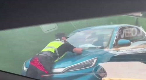 china man driving with officer on his vehicle