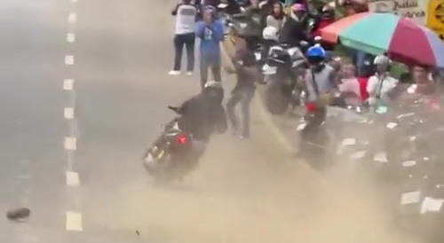 Idiot moped rider corners fast on sandy road, hits a dopey bystander.