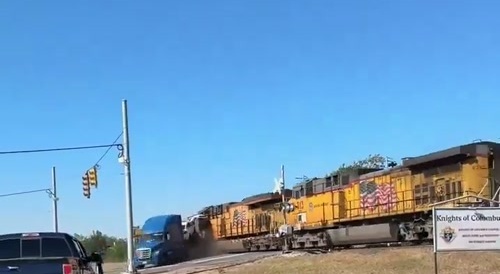 Train crashes into truck with cars on it