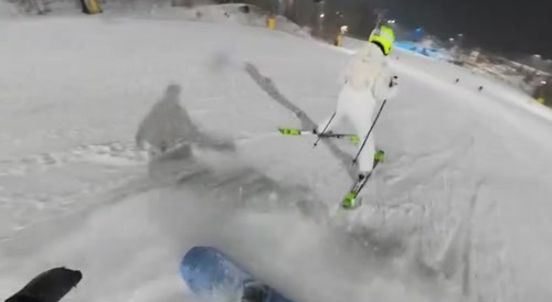 A snowboarder narrowly avoids hitting someone you can barely see until the very last second.