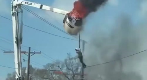 man frantically dangles from a burning cherry picker