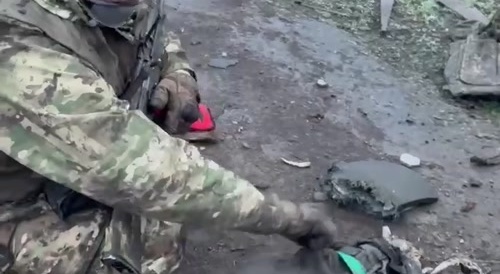 A Russian soldier laughs at the corpse of a Ukrainian.