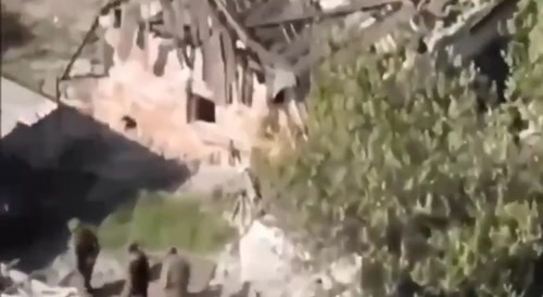 A large group of russian militants enters an exploding building.